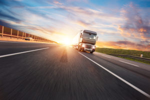 European truck vehicle on motorway with dramatic sunset light. Cargo transportation and supply theme.